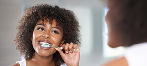 Woman brushing teeth as part of her preventive dentistry plan