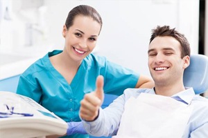 Smiling man in dental chair giving thumbs up