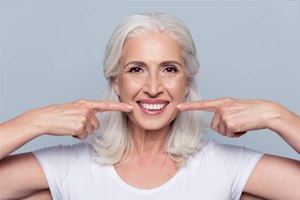 Older woman pointing to her beautiful smile