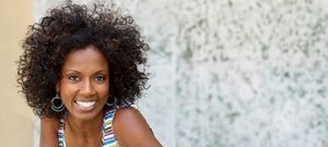 An older woman standing outside and smiling after cosmetic dental bonding