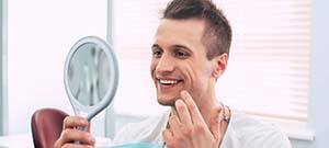 Man using mirror while visiting Lenox Hill emergency dentist