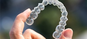 Someone holding up a clear aligner tray 