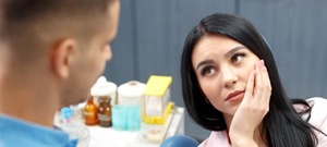 woman in pink shirt with toothache in dental chair