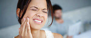 Woman in need of emergency dentistry holding jaw